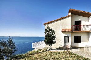  Dette praktisk indrettede feriehus er beliggende på en lille bakke og har en betagende udsigt over havet og øerne. Kun en trafikeret vej adskiller jer fra en stenstrand der kan nås via en fodgæng ...