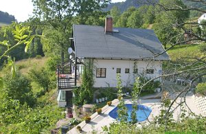  På en smuk skråning finder I dette velholdte feriehus med en åben terrasse, udendørs pool, solarium og en herlig udsigt på naturen. Fitnessmaskiner og sauna i huset. Adgang til hemsen via en sti ...